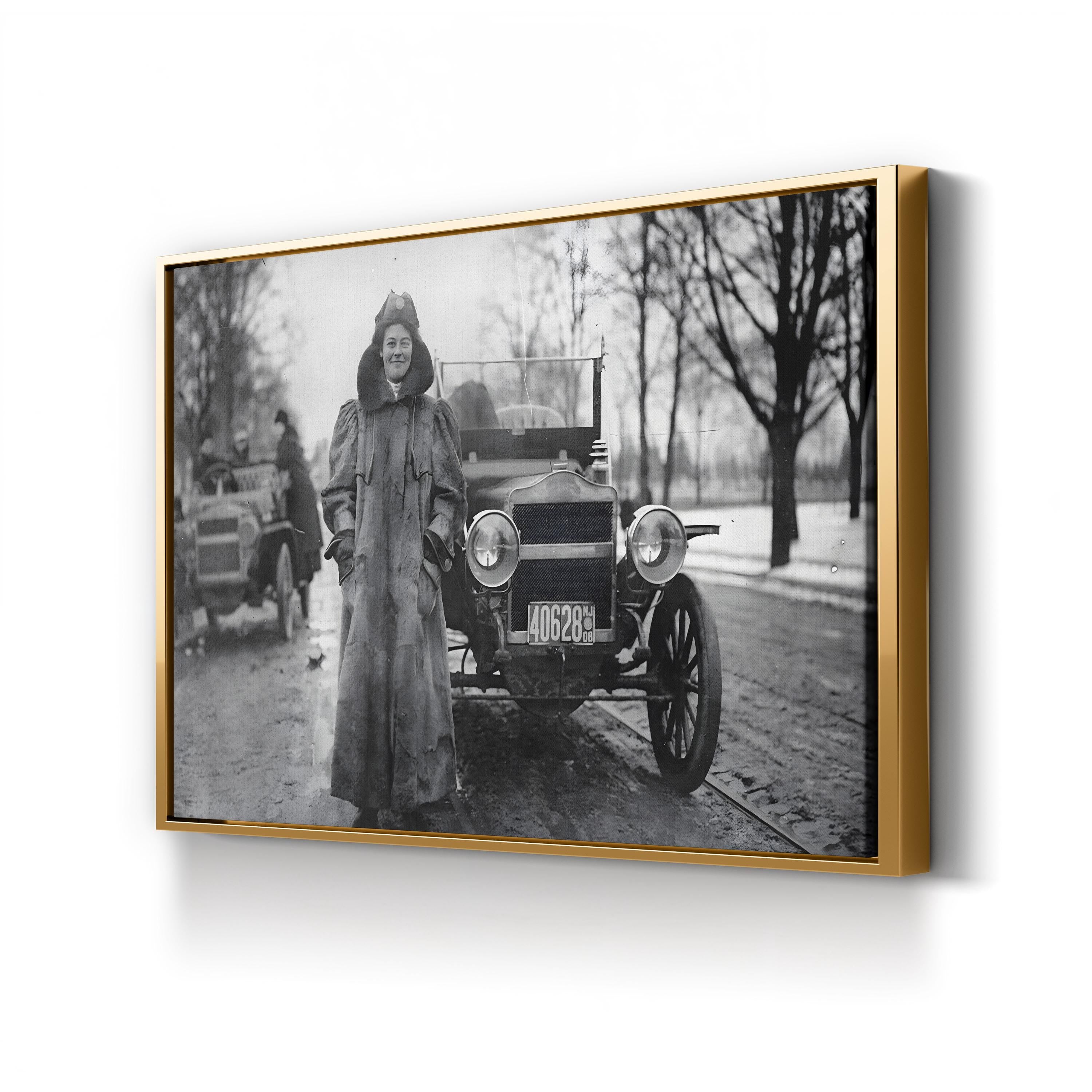 Framed black and white photograph of a woman standing next to an old car on a snowy street.