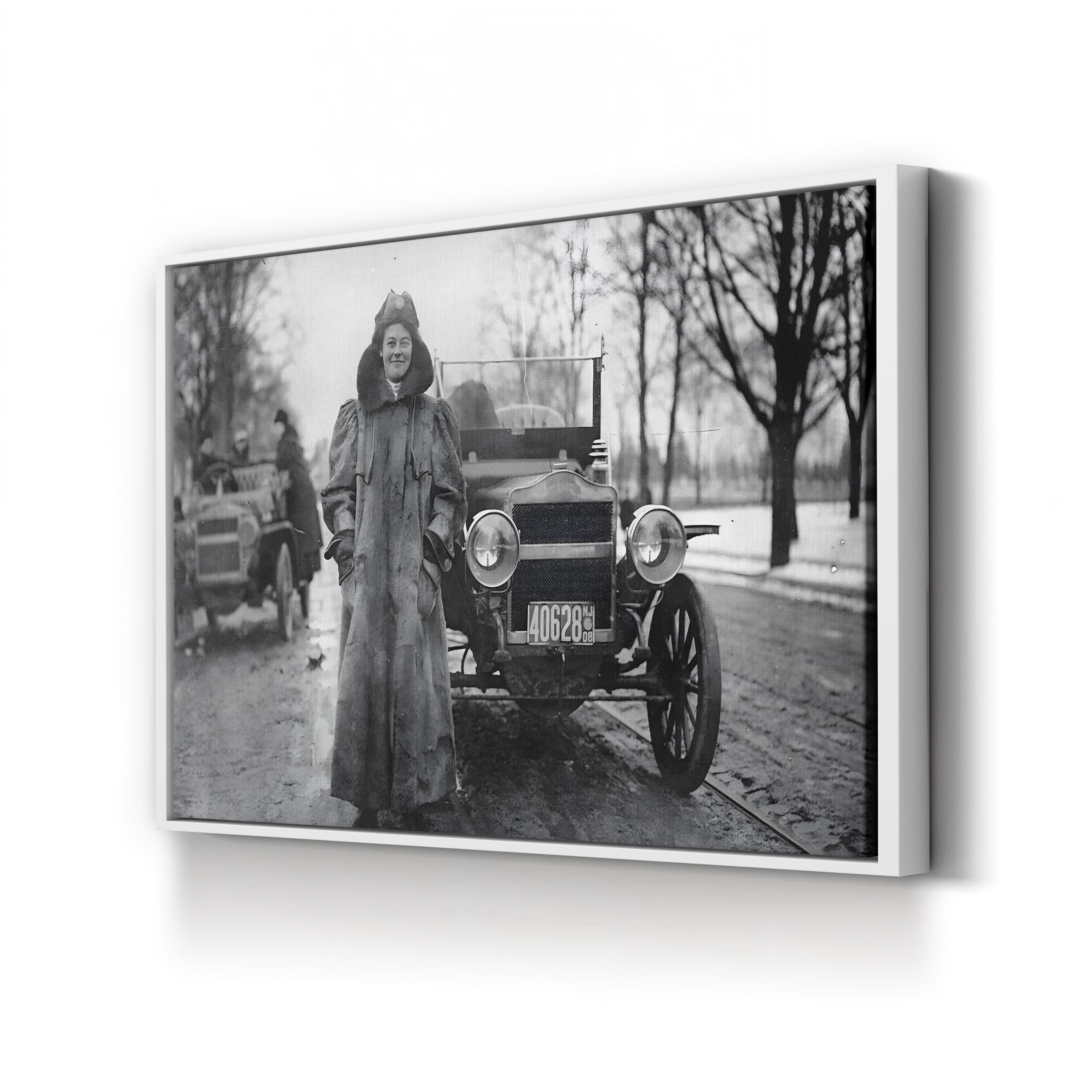 Vintage black and white photo of a woman standing next to an old car on a street.