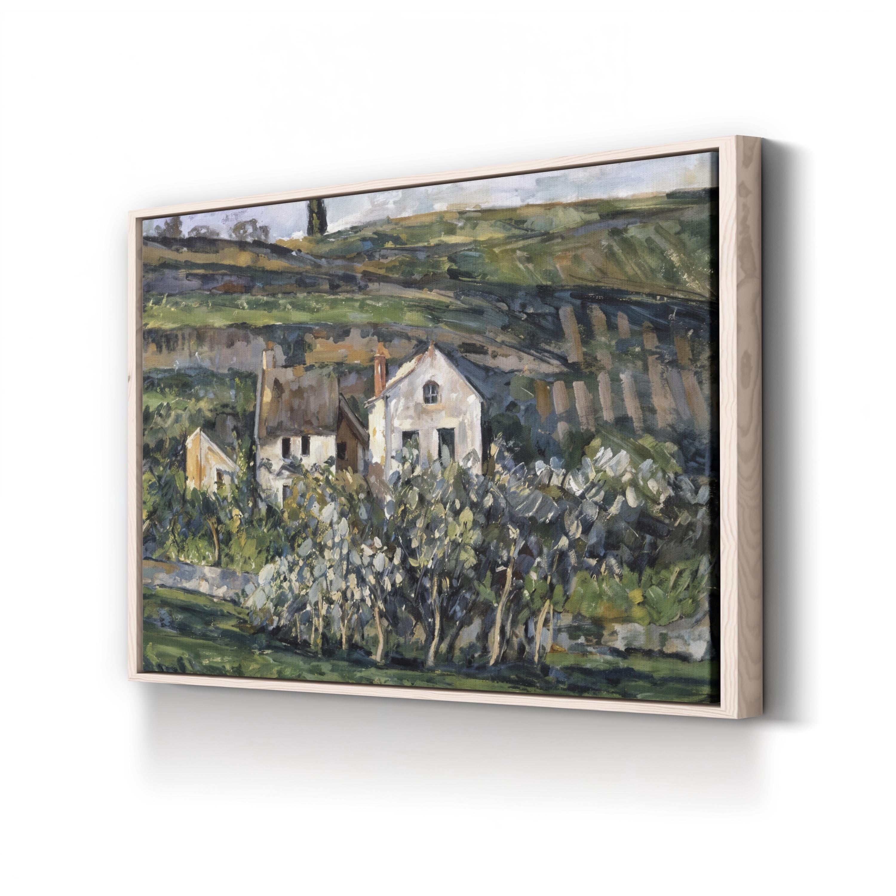 Framed painting of a landscape with houses and trees on a white wall