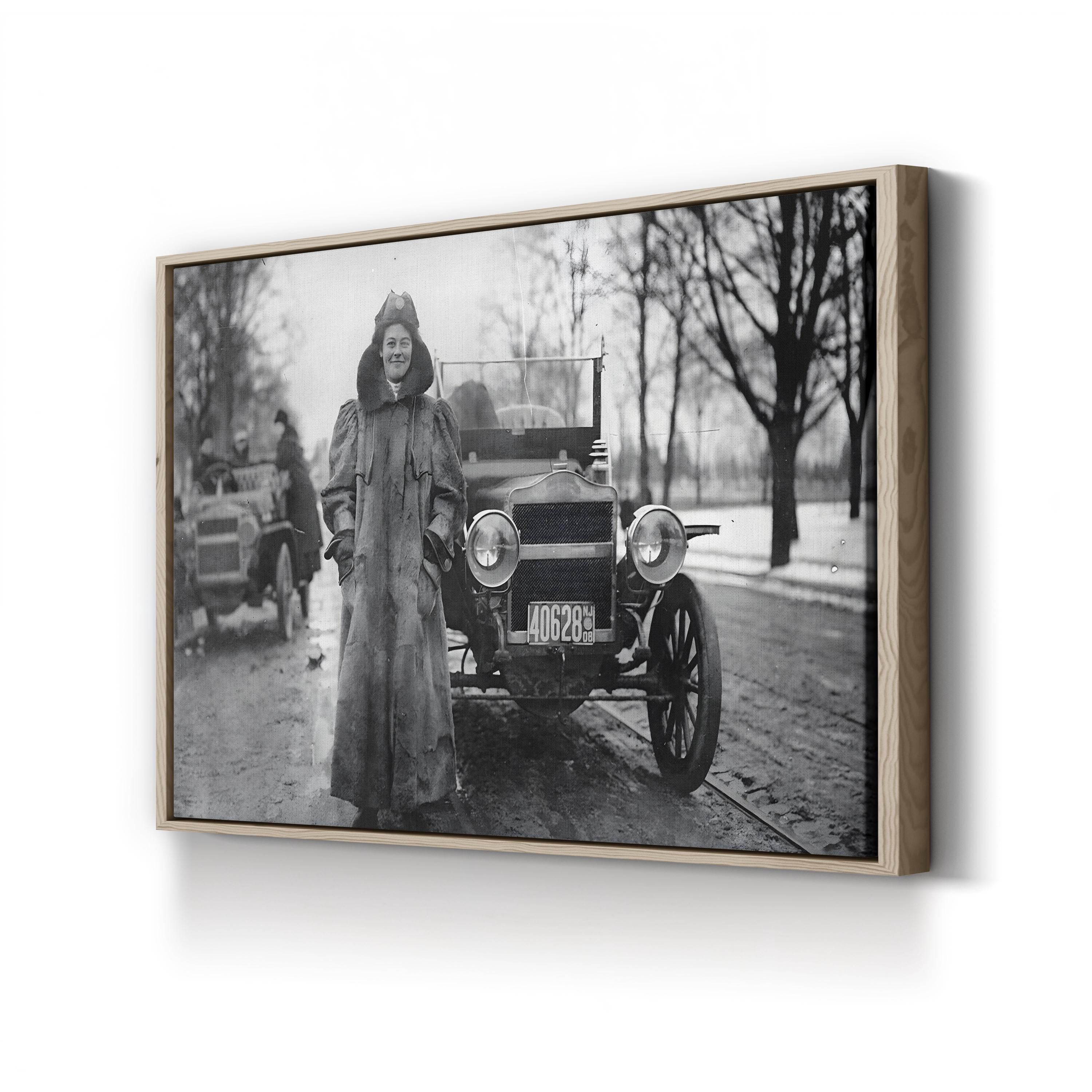 Framed black and white photograph of a woman standing next to an old car on a snowy street.