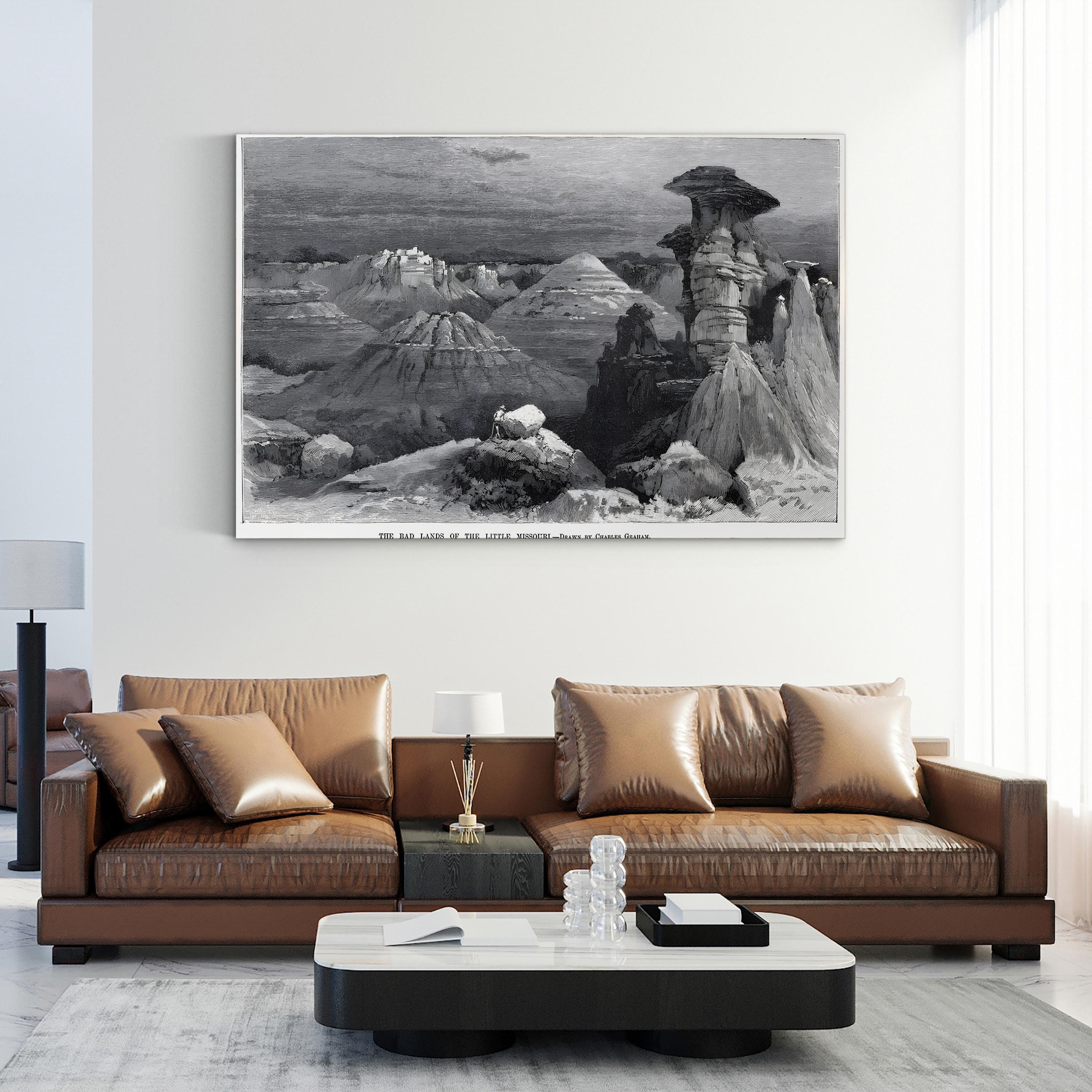 Brown leather sofa in a living room with a large framed landscape painting on the wall.