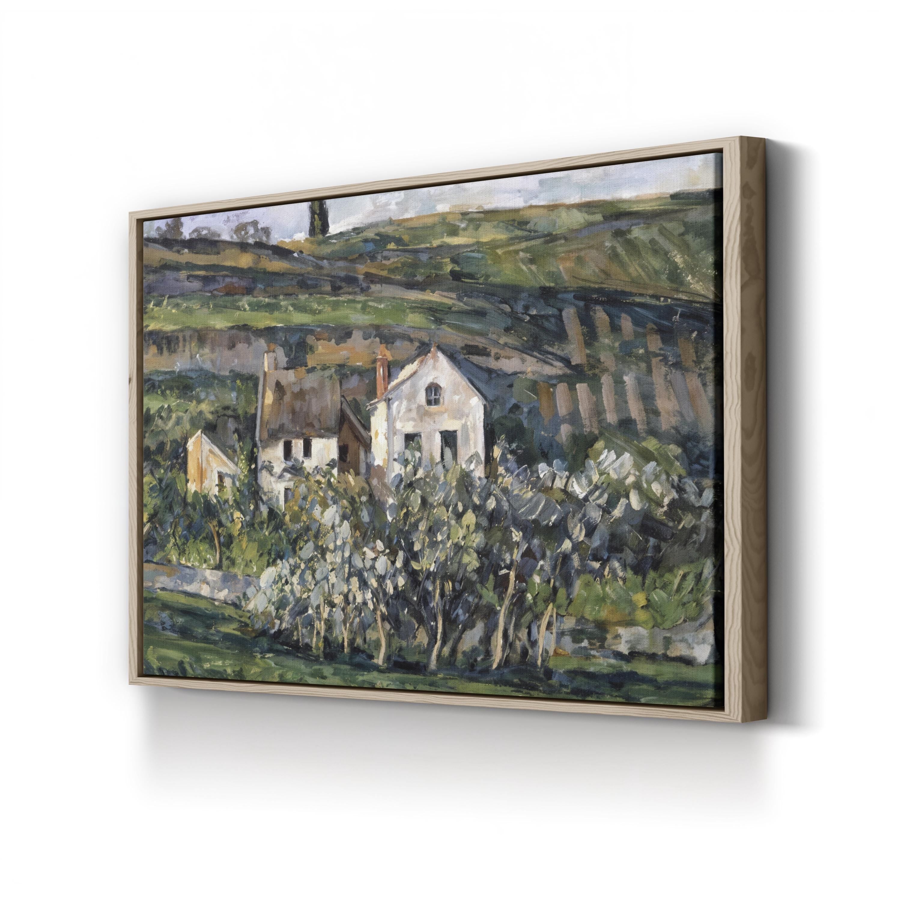 Framed painting of a landscape with houses and trees on a white wall