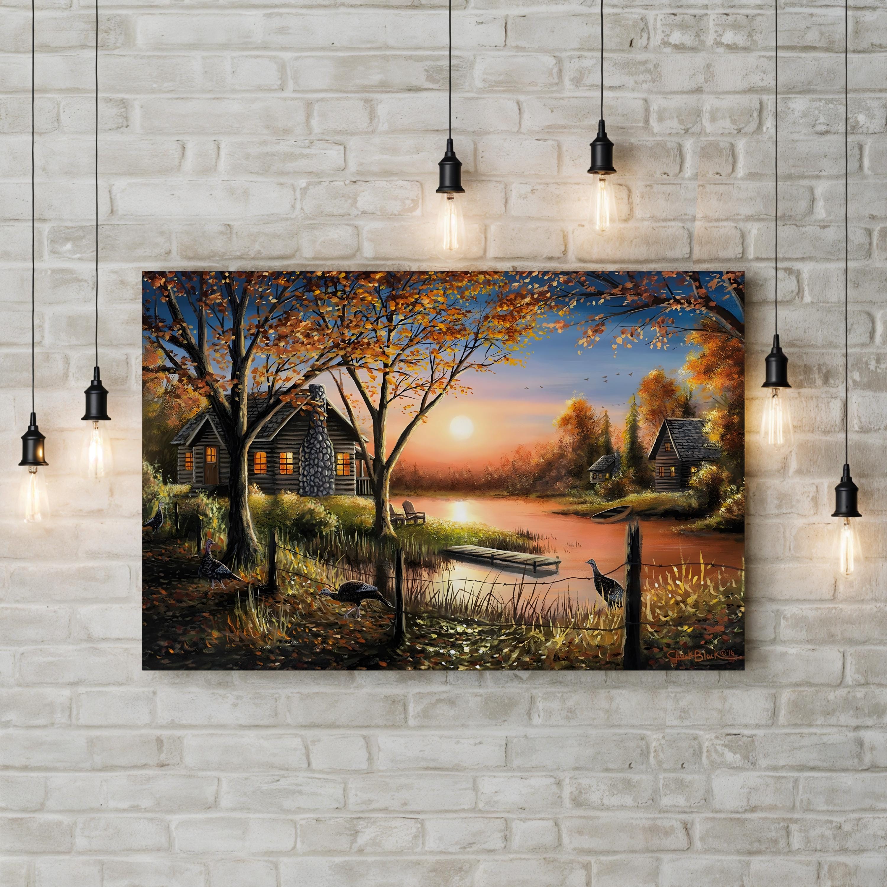 Landscape painting of a cabin by a lake with a sunset, hanging on a brick wall.